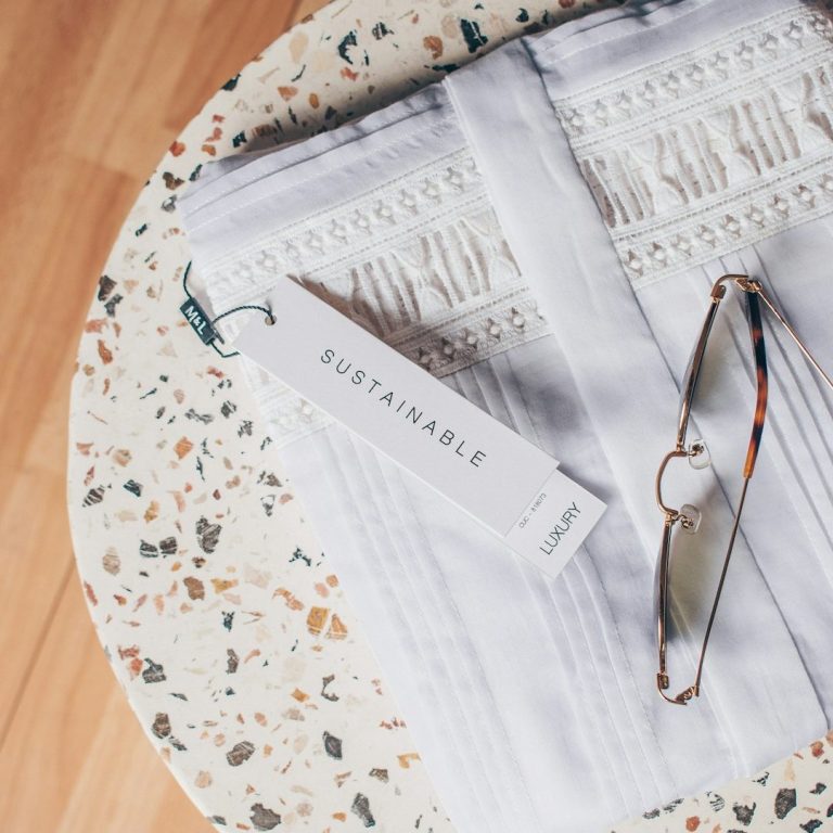 A white textured fabric folded on a round table with glasses and a tag beside it.