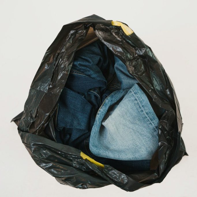A crumpled black bag containing various pairs of folded jeans.