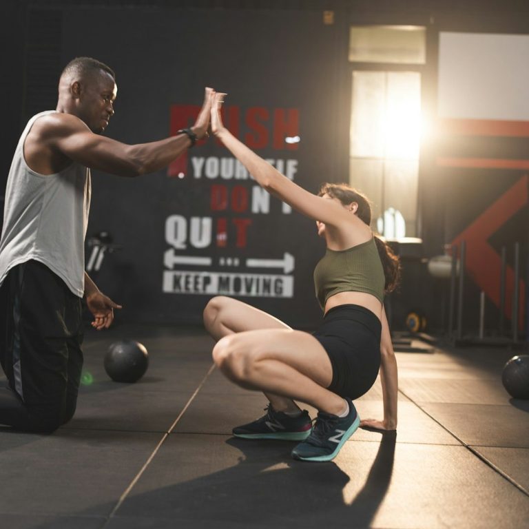 A man and woman high-five during a fitness workout in a gym.