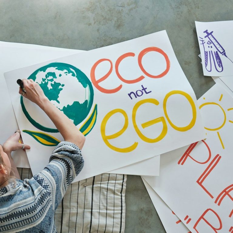 Person creating signs with messages promoting environmental awareness.