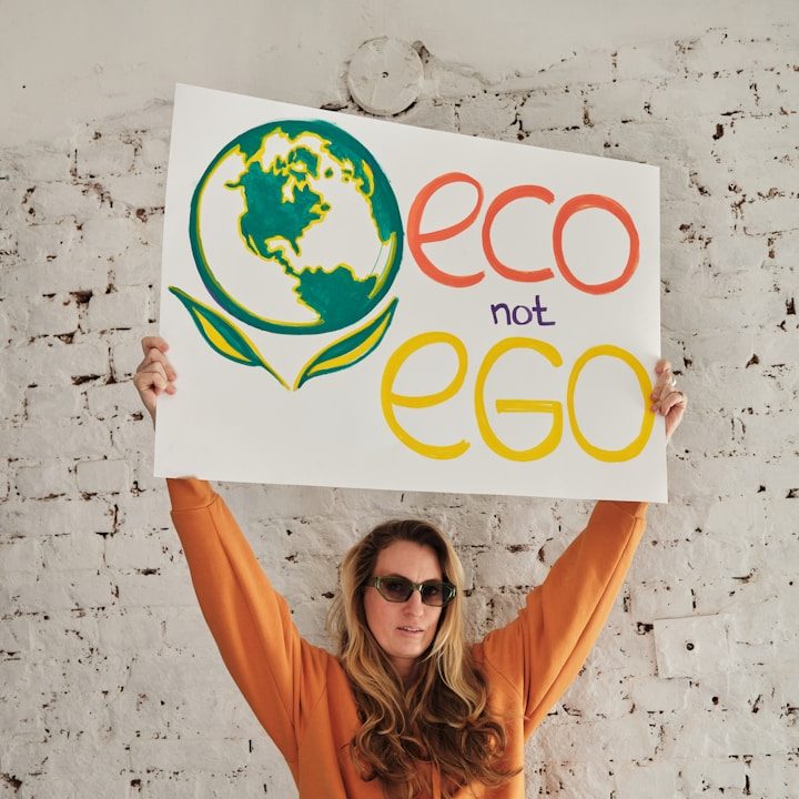 Person holding a sign that reads "eco not ego" with a globe and leaf design.